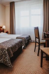 um quarto com uma cama, uma cadeira e uma janela em Hotel Korel em Poznań