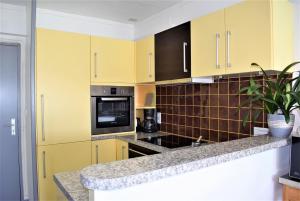 une cuisine avec des armoires jaunes et un comptoir dans l'établissement Appartement 2-4 pers VUE MER EXCEPTIONNELLE avec terrasse à PERROS-GUIREC - Ref 908, à Perros-Guirec