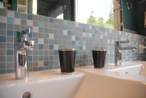 a bathroom sink with two cups on top of it at Seeloft - a Sharp Hotel in Herrliberg