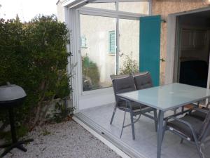 uma mesa de vidro e cadeiras num pátio em Villa climatisée 3 Pièces 100 m plage CAP D'AGDE em Cap d'Agde