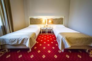two beds in a room with a red carpet at Hotel Sobienie Królewskie in Sobienie Szlacheckie