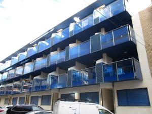 un edificio de apartamentos con balcones azules y una furgoneta aparcada enfrente en Apartamento Miracielo A Inmomart, en Peñíscola