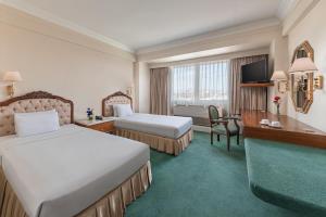um quarto de hotel com duas camas e uma secretária em Manila Prince Hotel em Manila