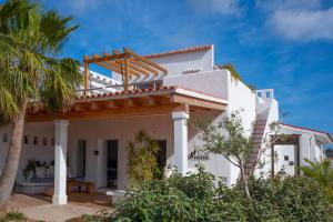uma casa branca com um telhado de madeira e uma palmeira em La Masía de Formentera em Sant Francesc Xavier