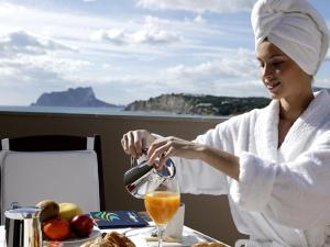 a woman sitting at a table in a bath robe pouring juice at La Sort Boutique Hotel in Moraira