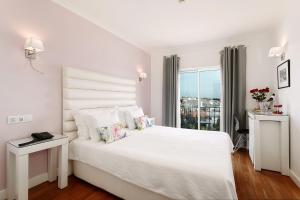 a white bedroom with a white bed and a window at Vila Sao Vicente Boutique (Adults Only) in Albufeira