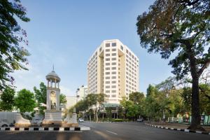 uma rua da cidade com uma torre de relógio e um edifício alto em Aryaduta Bandung em Bandung