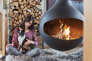 a woman sitting on the floor with a dog in front of a fireplace at Luxuslodge - Zeit zum Leben in Annaberg im Lammertal