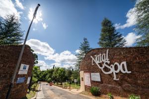 a brick wall with graffiti on it next to a street at Gooderson Natal Spa Hot Springs Resort in Paulpietersburg