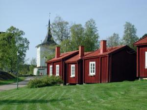 a small red building with a church in the background at Lövånger Kyrkstad in Lövånger
