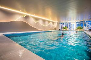 a man in a swimming pool in a hotel at Belvedere Swiss Quality Hotel in Grindelwald