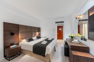 a bedroom with a large bed and a desk at Odysseia Hotel Kapetanios in Limassol