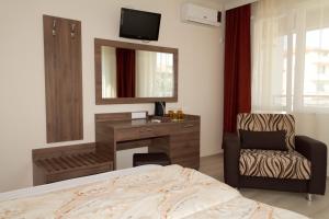 a bedroom with a bed and a desk and a chair at Guest House Dobi in Primorsko
