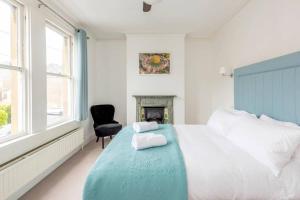een witte slaapkamer met een bed en een stoel bij Spacious House - 2 Double Rooms - Street Parking - Garden in Bath