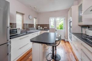 a kitchen with white cabinets and a black counter top at Spacious House - 2 Double Rooms - Street Parking - Garden in Bath