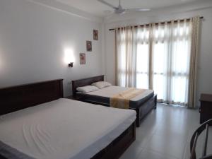 a bedroom with two beds and a window at Turtle Paradise Villa in Kosgoda