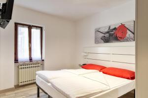 Una cama blanca con almohadas rojas en un dormitorio en Casa Raffaele, en Malcesine 4 fotos más