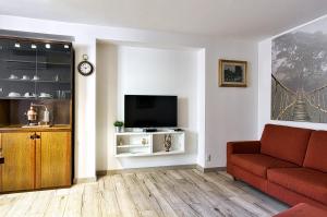 un salon avec un canapé rouge et une télévision dans l'établissement Casa Raffaele, à Malcesine