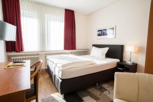 a small hotel room with a bed and a desk at Hotel Bürger in Siegen