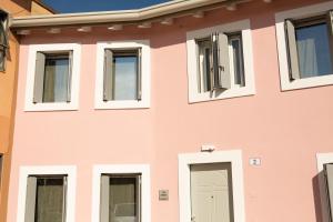 a pink building with windows and a door at CORTE QUADRIFOGLIO in Verona