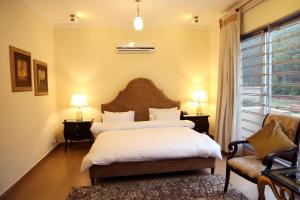 a bedroom with a bed and a chair and a window at Butterfly Guest House Phase 7 Bahria Town in Rawalpindi