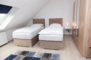2 bedden in een zolderslaapkamer met een tapijt bij T&K Apartments near Messe Fair Trade Düsseldorf und Airport 3A in Duisburg