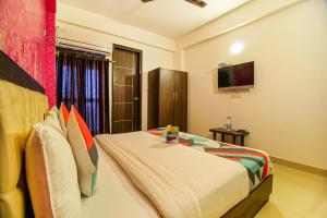 um quarto com uma cama e uma televisão na parede em FabExpress T P Suite em Nova Deli