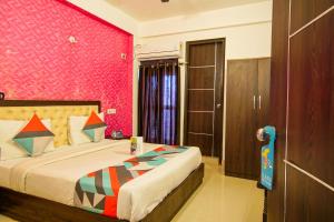 Un dormitorio con una cama y una pared rosa. en FabHotel TP Suites, en Nueva Delhi