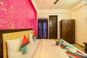 um quarto com uma cama com uma parede rosa em FabExpress T P Suite em Nova Deli