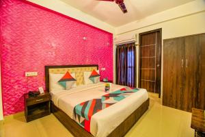 Un dormitorio con una cama grande y una pared rosa en FabHotel TP Suites, en Nueva Delhi