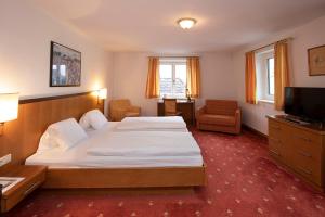 a hotel room with a bed and a television at Keramikhotel Goldener Brunnen in Gmunden