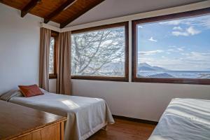 a bedroom with two beds and a large window at Utaka Cabañas y Apartamentos in Ushuaia