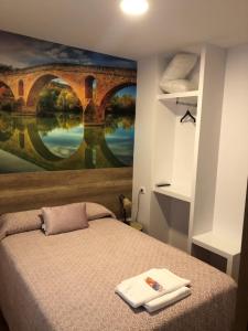 a bedroom with a large painting of a bridge at Pensión Mavi in Los Arcos