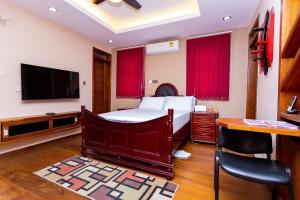 a bedroom with a bed and a flat screen tv at ASK Apartments in Accra