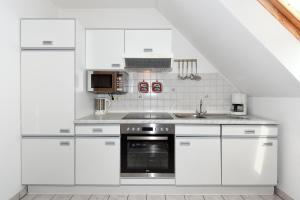 a white kitchen with white cabinets and a sink at Ferienwohnung Backbord in Carolinensiel