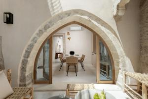 ein Torbogen in einem Raum mit einem Tisch und Stühlen in der Unterkunft Sutor Chic Manor in Rethymno