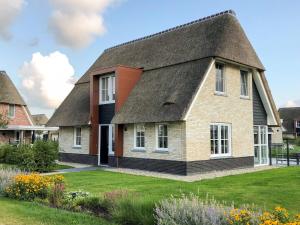 una casa con techo de paja en Thatched villa with lounge set, right at the water, en Delfstrahuizen