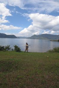 un enfant est debout dans l'herbe près d'une masse d'eau dans l'établissement Imuhira Campsites&CBT, à Macuba