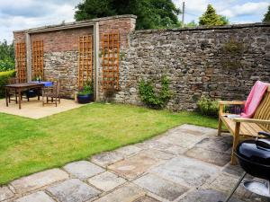 a garden with a stone wall and a table and chairs at Garden Cottage in Richmond +3 photos