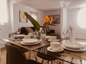 stół jadalny z talerzami, okularami i kwiatami w obiekcie Casa do Manuel Maria w mieście Estreito da Calheta