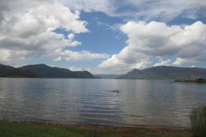 un pato nadando en un lago con montañas en el fondo en Imuhira Campsites&CBT, en Macuba