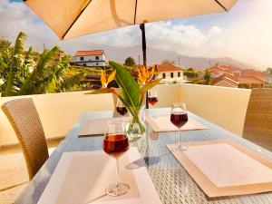 a table with two glasses of wine on a balcony at Casa do Manuel Maria in Estreito da Calheta