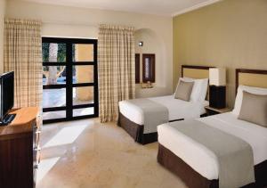 a hotel room with two beds and a television at Mövenpick Resort & Spa Dead Sea in Sowayma
