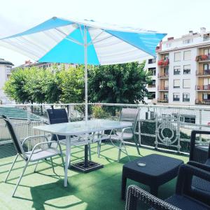 a table and chairs with an umbrella on a balcony at Txoko Maitea Pentsioa in Urnieta