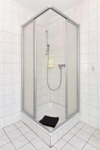 La salle de bains carrelée de blanc est pourvue d'une douche et d'une serviette noire. dans l'établissement Ferienwohnung Backbord, à Carolinensiel