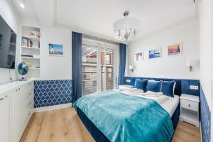 a blue and white bedroom with a bed and a window at Apartamenty Sun & Snow Klifowa Rewal in Rewal
