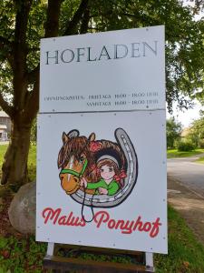 Ein Schild für Malls Ponyot mit einem Pferd drauf. in der Unterkunft Malus Ponyhof in Todenbüttel