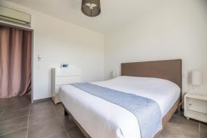 Un dormitorio con una gran cama blanca y una ventana. en Résidence Pierre & Vacances Premium Les Villas de Porto-Vecchio, en Porto Vecchio