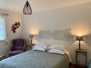 a bedroom with a bed and a purple chair at Le Bois des Pierres in Conteville