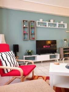 ein Wohnzimmer mit einem roten Stuhl und einem TV in der Unterkunft City House 3 in Kalamata
